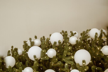 Christmas tree with white ornaments against a blurred background of lights