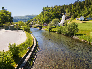 Aerial drone view of the powerful Hellesyltfossen waterfall crashing into the river in the scenic village of Hellesylt, Norway.