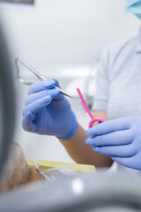 Vertical close up of gloved hands selecting orthodontic elastic ligature for braces