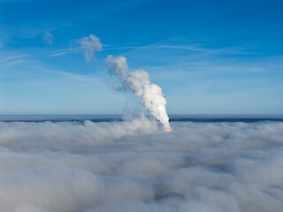 Aerial drone view of industrial chimneys emitting steam above thick fog and clouds on a sunny day, power plant and factory landscape. Panorama above clouds in fog in sunny day. Clouds factory