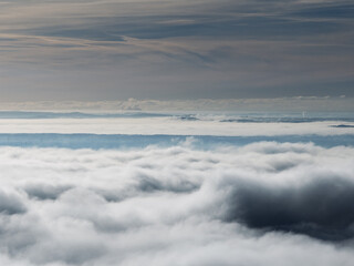 Aerial drone view of industrial chimneys emitting steam above thick fog and clouds on a sunny day, power plant and factory landscape. Panorama above clouds in fog in sunny day. Clouds factory