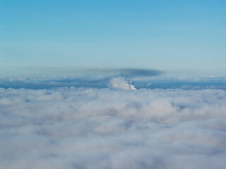 Aerial drone view of industrial chimneys emitting steam above thick fog and clouds on a sunny day, power plant and factory landscape. Panorama above clouds in fog in sunny day. Clouds factory