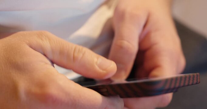 Close-up of hands typing on a smartphone after it was previously dropped. The phone still works, showing daily digital habits and resilience.
