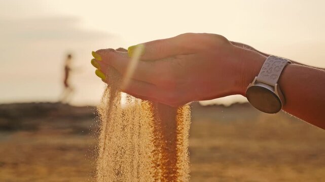 Slow motion closeup of hands letting sand fall in warm sunset spiritual mood