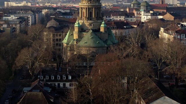 Aerial footage flying towards Baroque Christuskirche, protestant church in Mannheim, Germany, with city skyline background