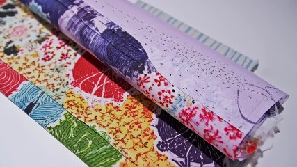 Rolled papers with various colorful patterns and a purple, textured top layer - Powered by Adobe