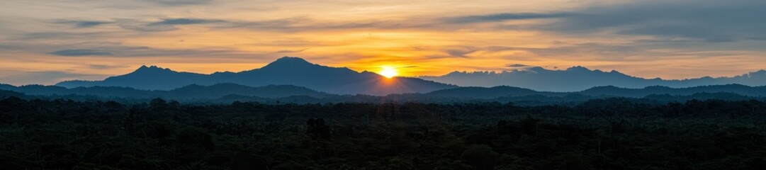 Obraz premium Panoramic view of lush green forest canopy and layered blue mountain ranges at sunrise