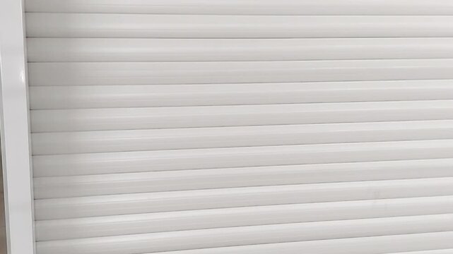 White roller shutter close up clean slats and soft light camera movement bottom to top versatile background for retail security corporate videos and design use