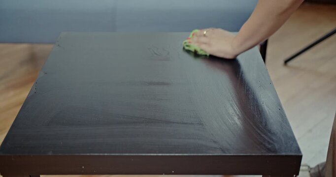 Enjoy the crisp, satisfying sounds as a person's hand meticulously wipes a dusty wooden table clean with a microfiber cloth. This video captures the simple act of cleaning with immersive audio.
