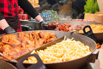 vendor fries meat and sausage on the grill in the city center at the Christmas market in Krakow Poland