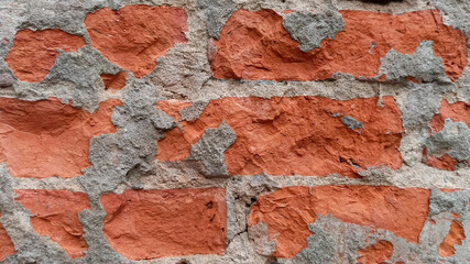 Close up of weathered red brick wall with crumbling grey mortar texture