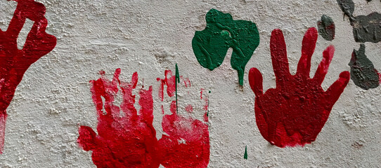 Red and green handprints on textured white wall image