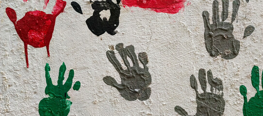 Red green black grey handprints on textured white wall paint