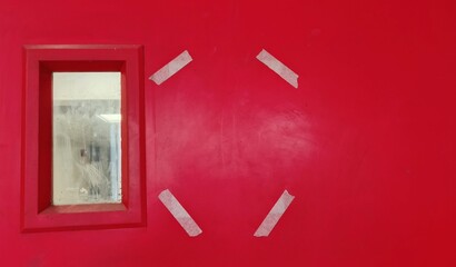 Red surface with small window and taped hexagon shape wall door