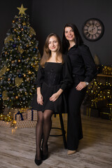 Two women are posing for a picture in front of a Christmas tree
