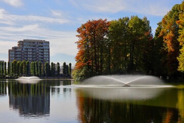 水面に映り込む住宅と木々の前に２つの噴水　埼玉県別所沼公園