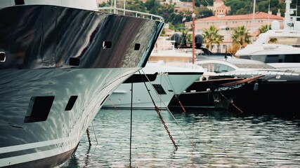 Close up of a yacht's metallic hull reflecting the surrounding marina and water ripples