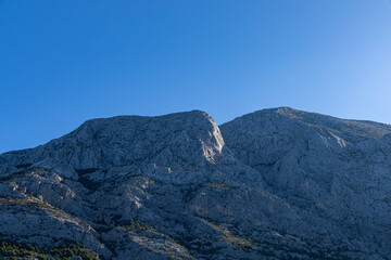 Fototapeta premium Gray rocks with small vegetation against the sky. Mountain landscape, Croatia. copy space