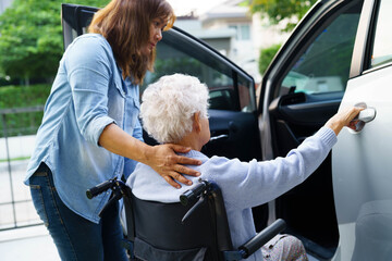 Caregiver help Asian elderly woman disability patient use wheelchair to get in car.