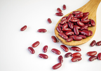 Red bean seeds on a wooden spoon on a white background