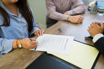 Woman signing divorce agreement documents with lawyer