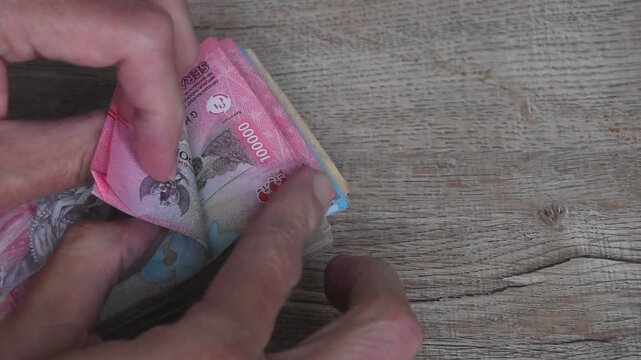 indonesia rupiah banknote arranging on wooden table and hand couting them