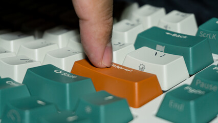 Macro photo of finger pressing orange Enter key on mechanical keyboard, sharp detail on finger and keycap, blurred background enhances depth perception.