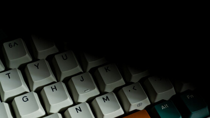 Minimalist shot of keyboard partially covered by shadow, focus on Y to K keys, creating a moody contrast between illuminated and darkened area.