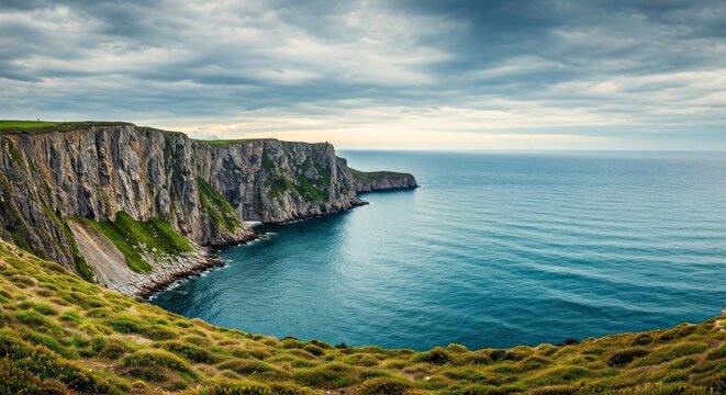 Dramatic coastal cliffs meet the blue sea under a cloudy sky - Powered by Adobe