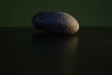 Smooth Stone Reflecting on Dark Surface, Minimalist Still Life.