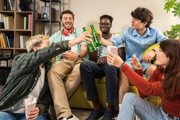 Fototapeta premium Diverse group of friends toasting with beer at home party. Multicultural young people celebrating, concept of friendship, community, and generation z.