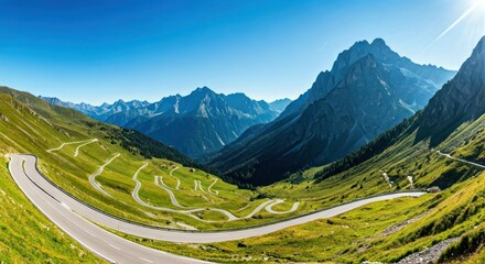 Panoramic view of winding road through lush, green mountain valley under clear blue sky