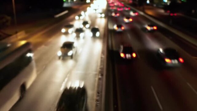 Blurry nighttime highway scene with speeding cars and trucks on a multi-lane road with illuminated headlights and taillights.