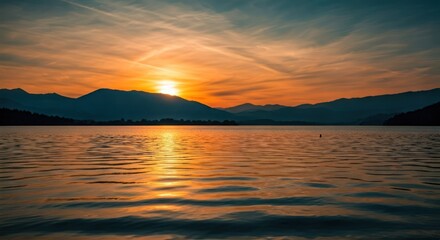 Sunrise hues cast over a serene lake, mountains silhouetted in the distance