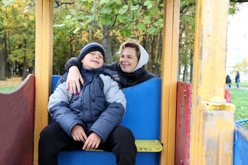 Obraz premium A woman and her son are playing on a playground in an autumn park.