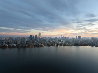 Fototapeta premium Hanoi skyline reflecting on West Lake during early dawn with soft pastel sky and city lights.