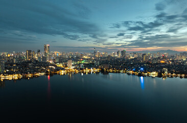 Fototapeta premium Evening view of West Lake with shimmering city lights reflecting across the calm water and distant skyline.