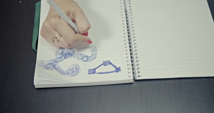 A close-up view captures a hand drawing intricate, abstract patterns in a lined spiral notebook. The clear, scratchy sounds of the pen on paper are distinctly audible, enhancing the creative process.