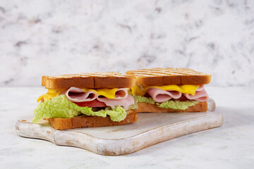 Delicious sandwich with ham, cheese, tomato and lettuce on toasted bread. Perfect lunch or snack idea