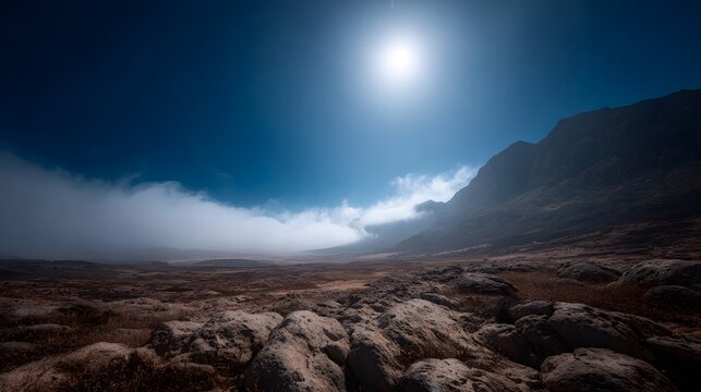 Dramatic mountain landscape with rocky terrain rolling fog and bright sun under a deep blue sky - Powered by Adobe