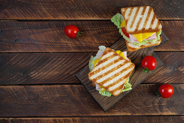 Delicious sandwich with ham, cheese, tomato and lettuce on toasted bread. Perfect lunch or snack idea