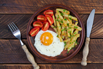Homemade morning breakfast with fried egg, crispy potato and fresh tomatoes