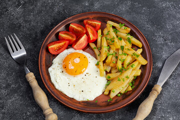 Homemade morning breakfast with fried egg, crispy potato and fresh tomatoes