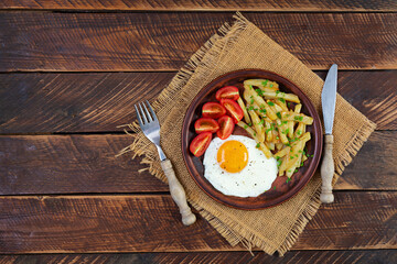 Homemade morning breakfast with fried egg, crispy potato and fresh tomatoes