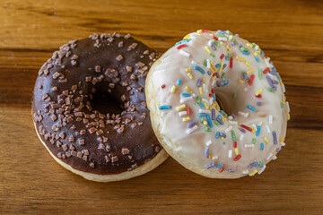 chocolade and vanilla glazed donuts on wooden surface close up shallow depth of field