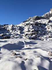 Obraz premium Snow blankets rocky slopes under clear skies.