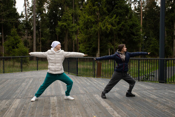 Bald woman with cancer performing yoga pose outdoors, concept of self-care, healthy lifestyle, and oncology recovery.