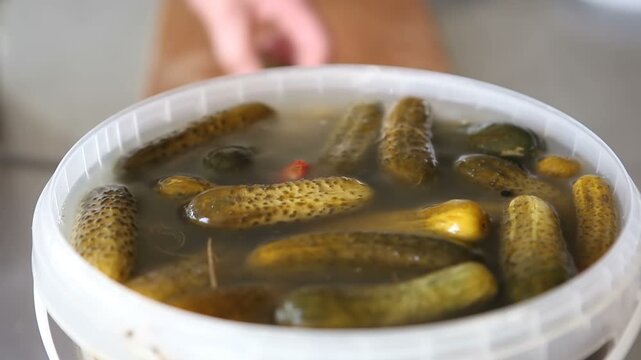 The cook takes pickles out of a bucket and slices them. Macro.