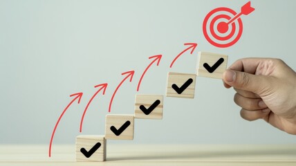 Hand placing final checkmark on steps leading to a bullseye target, symbolizing goal achievement and success.