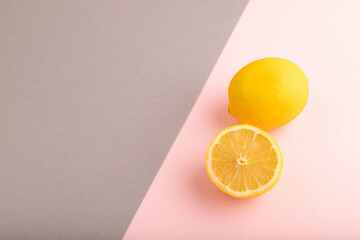 Yellow Lemon Cut in half on gray and pink pastel paper, Side view, copy space